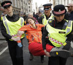 Police remove an Extinction Rebellion climate change protester who blocked a road outside the Goldman Sachs office in the City of London, Thursday, April 25, 2019. The non-violent protest group, Extinction Rebellion, is seeking negotiations with the government on its demand to make slowing climate change a top priority. (AP Photo/Matt Dunham)