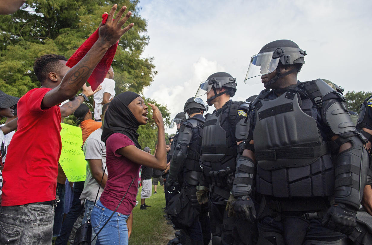 A protester yells at police officers in riot gear after being forced off the motor way in front of the the Baton Rouge Police Department Headquarters in Baton Rouge, La., Saturday, July 9, 2016. Several hundred protesters, including members of the New Black Panther party, blocked the road causing police to close the road and move the crowd with riot police. (AP Photo/Max Becherer)