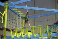 A youth tries out the Sky Trail obstacle course during the International Association of Amusement Parks and Attractions convention Tuesday, Nov. 19, 2019, in Orlando, Fla. (AP Photo/John Raoux)