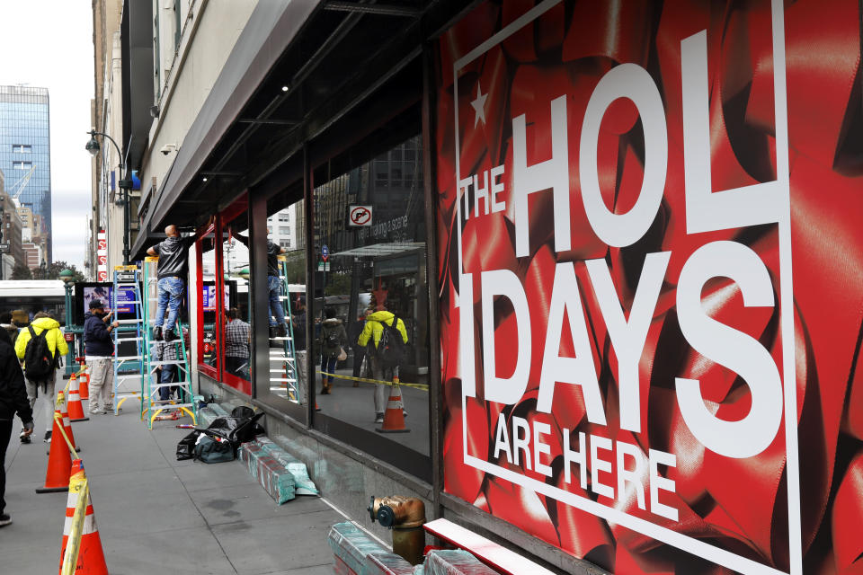 FILE - In this Tuesday, Nov. 5, 2019 file photo workers trim windows for the upcoming holiday season at the Macy's flagship store in New York. Macy’s cut its profit and sales expectations for the year after posting its first comparable store sales decline in almost two years, Thursday, Nov. 21. The company is citing the late arrival of colder weather, meager tourist business, weak traffic at some malls and problems on its website. (AP Photo/Richard Drew, File)