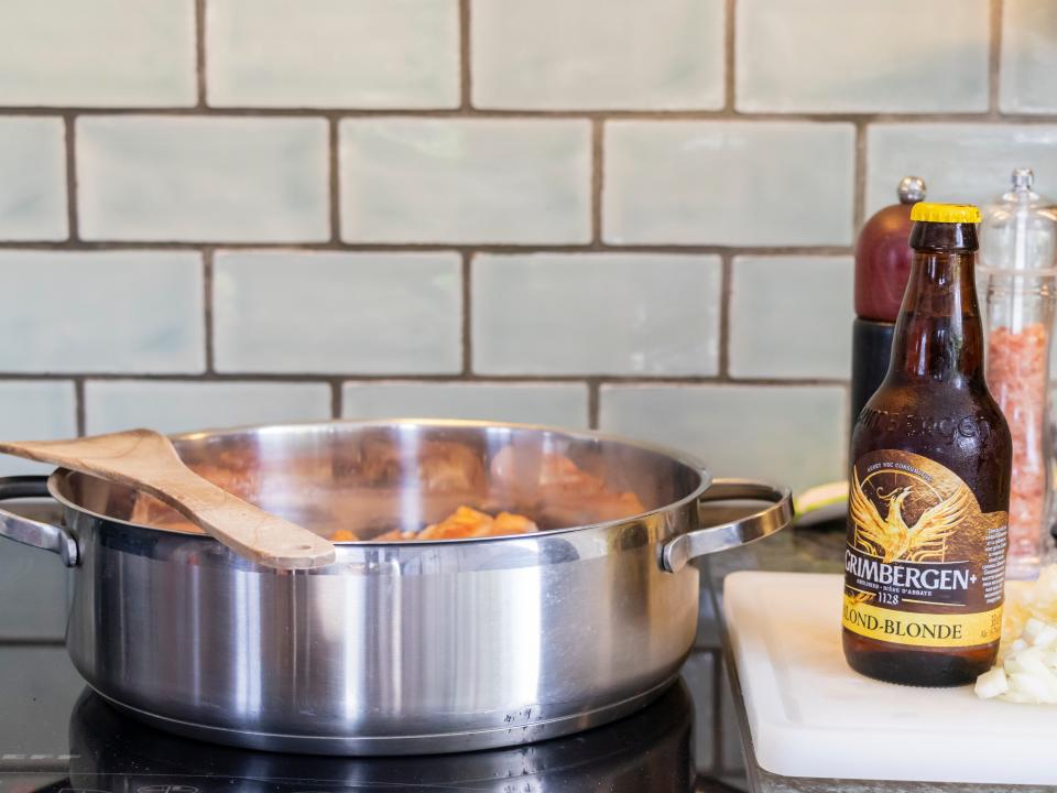 Beer bottle next to cooking pot with food in kitchen