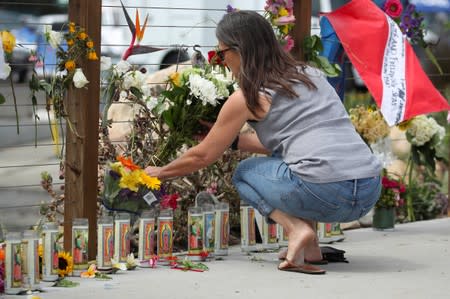 A woman places flowers at a makeshift memorial near Truth Aquatics as the search continues for those missing in a pre-dawn fire that sank a commercial diving boat near Santa Barbara, California