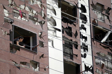 A civilian looks out from a window of a damaged building at the site of a car bomb on the outskirts of the Sayeda Zeinab district south of Damascus, Syria, April 25, 2016. REUTERS/Omar Sanadiki TPX IMAGES OF THE DAY