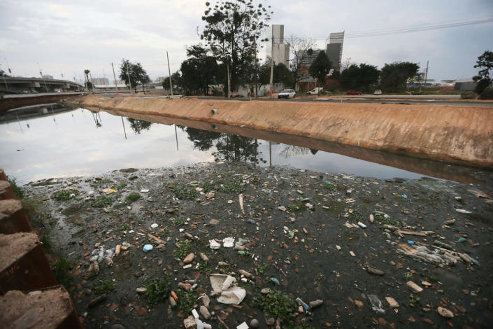<p>A polluted canal runs past the Vila Autodromo 'favela’ community next to the Olympic Park (BACKGROUND) in the Barra da Tijuca neighborhood on July 16, 2016 in Rio de Janeiro, Brazil. Nearly all of the residents of the Vila Autodromo 'favela’ community in the area had their properties controversially demolished, after receiving compensation, for their homes which were located directly adjacent to the Olympic Park under construction for the Rio 2016 Olympic Games. Around 20 remaining families who continued in resistance will remain with the Rio government constructing them new homes on the property. (Mario Tama/Getty Images)