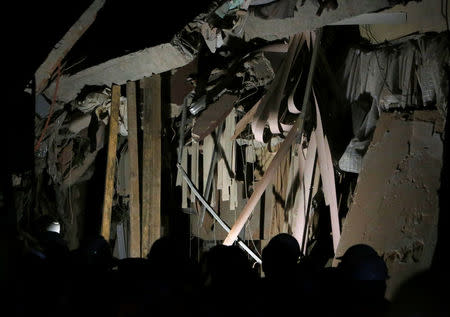 Rescue workers stand in front of the remains of a collapsed building after an earthquake hit Mexico City, Mexico September 20, 2017. REUTERS/Ginnette Riquelme