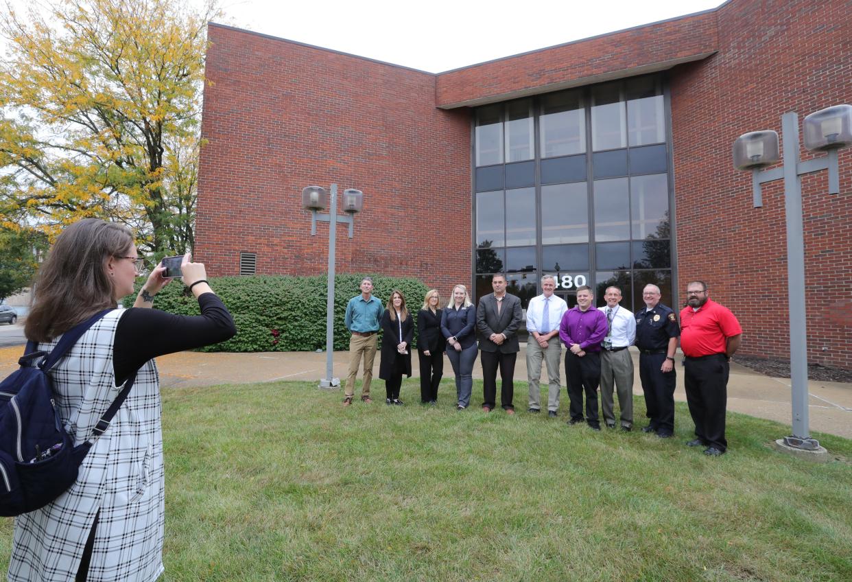 Emma Hutchinson, administrative coordinator to Barberton Mayor Bill Judge, photographs the mayor with city and court administrators in front of the old FirstMerit building Thursday on West Tuscarawas Avenue. Barberton is finalizing plans to purchase the building and use it as a new City Hall.