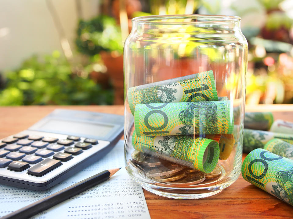 Image of Australian money in a jar, on a table with calculator and pencil