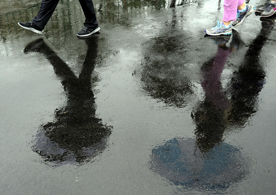 Spectators walk to the first tee in the rain during the second round of the RBC Heritage golf tournament in Hilton Head Island, S.C., Friday, April 18, 2014. (AP Photo/Stephen B. Morton)