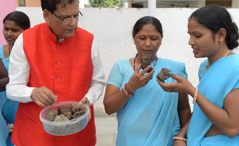 'Toilet guru' Pathak (L) shows compost prepared from human excrement to visitors at his charity's campus in New Delhi