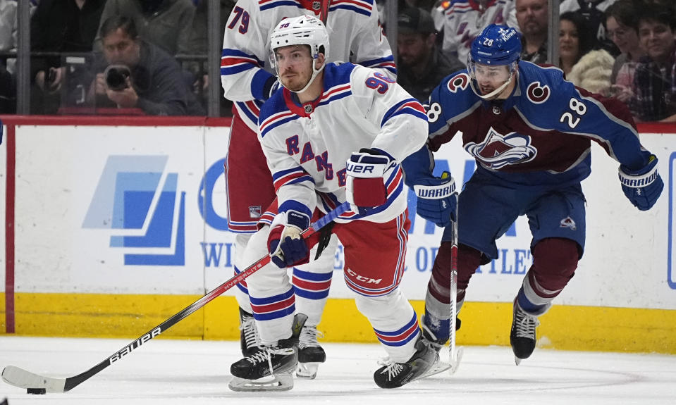 New York Rangers center Jack Roslovic, left, picks up the puck as Colorado Avalanche left wing Miles Wood defends during the second period of an NHL hockey game Thursday, March 28, 2024, in Denver. (AP Photo/David Zalubowski)