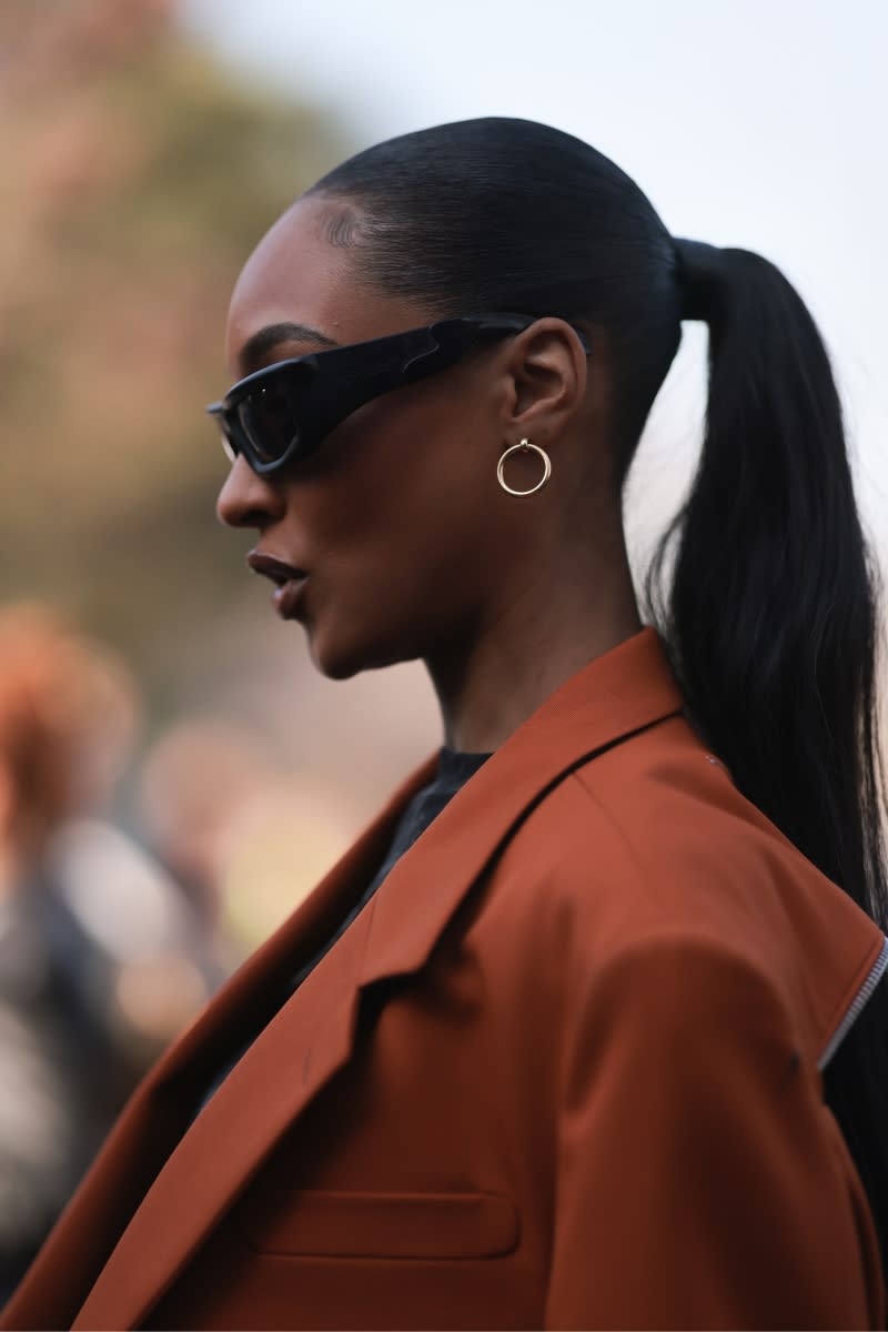 Jourdan Dunn is seen with a low ponytail, whilst  wearing an orange brown blazer, black shirt, black sunglasses and golden earrings, outside Off White, during Pariser Fashion Week on March 02, 2023 in Paris, France.