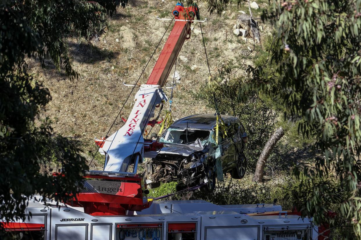 A crane is used to lift a vehicle following a rollover accident involving golfer Tiger Woods, Tuesday, Feb. 23, 2021, in the Rancho Palos Verdes section of Los Angeles.