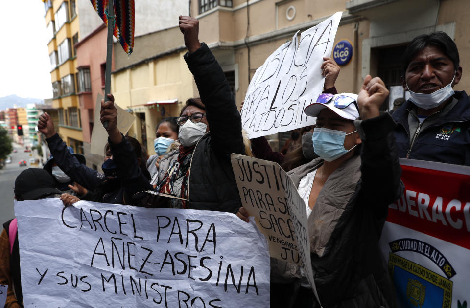 Una mujer sostiene una pancarta mientras la gente protesta contra la ex presidenta interina de Bolivia, Jeanine Áñez, frente a la estación de policía donde está detenida en La Paz, Bolivia, el domingo 14 de marzo de 2021. (Foto AP/Juan Karita)