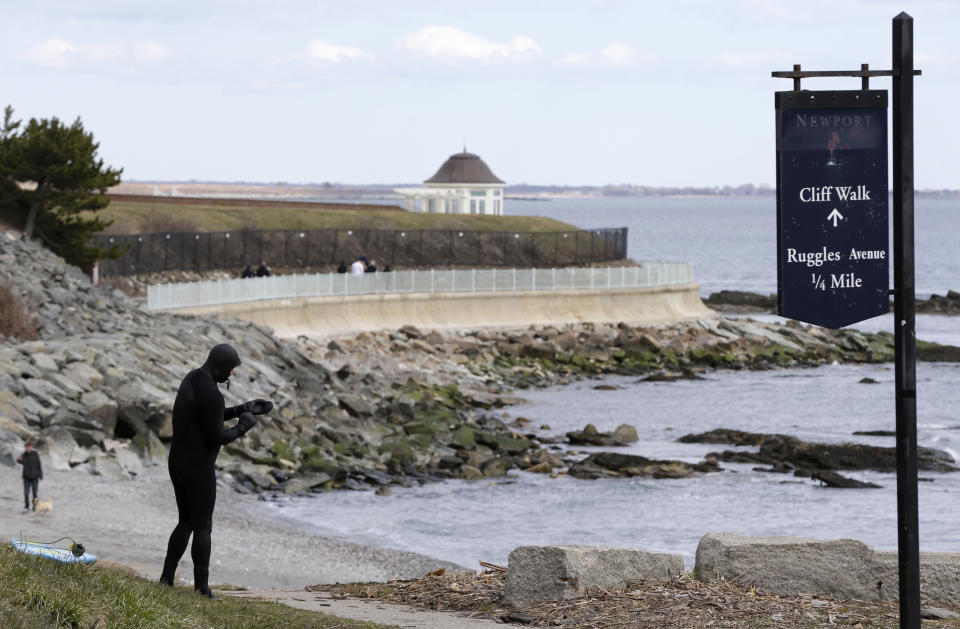 FILE - In this Wednesday, March 27, 2013 photo surfer Dave Livingston, of Newport, R.I., left, removes his gloves while standing near a portion of the Cliff Walk, in Newport, R.I. The Cliff Walk is one of a number of free attractions in Rhode Island that can be visited in the Summer. (AP Photo/Steven Senne, File)