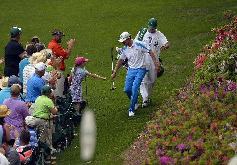 Jonas Blixt of Sweden fist-bumps with a young girl as he makes his way to play a shot during the final round of the 78th Masters Golf Tournament, at Augusta National Golf Club in Georgia, on April 13, 2014