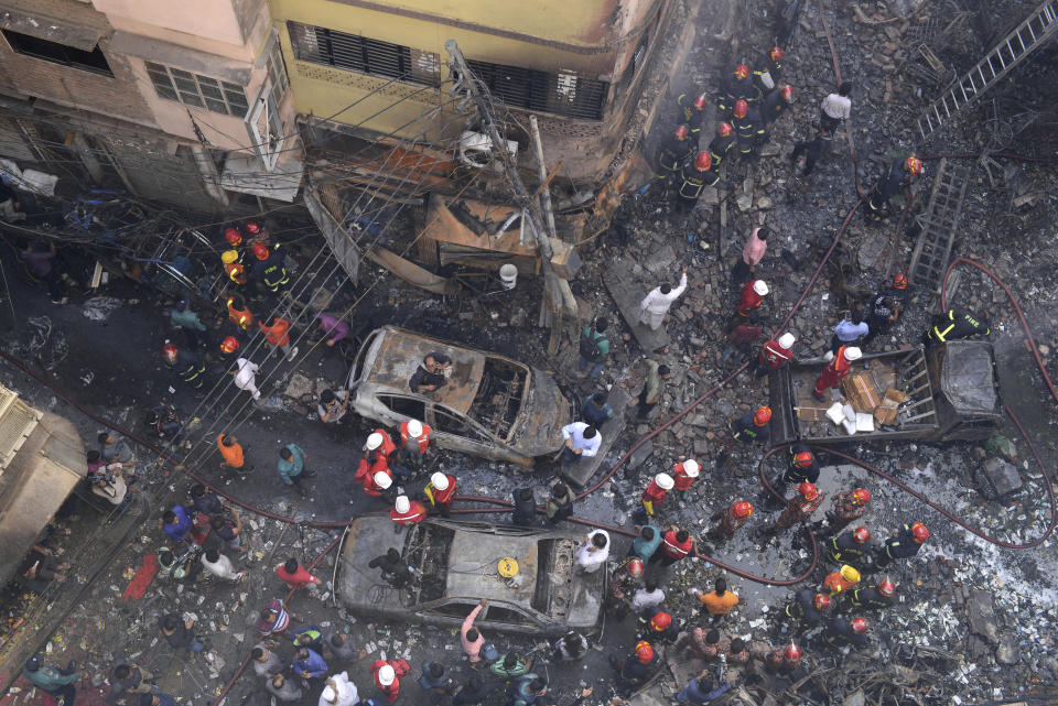 Rescuers stand at the site of a late Wednesday night fire in Dhaka, Bangladesh, Thursday, Feb. 21, 2019. A devastating fire raced through at least five buildings in an old part of Bangladesh's capital and killed scores of people. (AP Photo/Mahmud Hossain Opu )