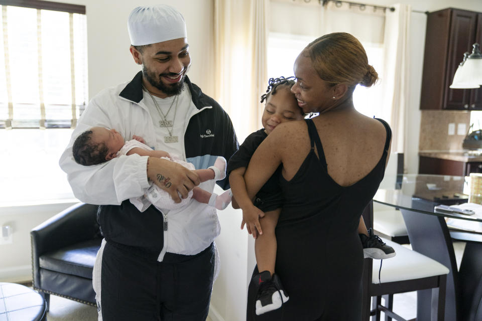 Aaliyah Wright, 25, of Washington, right, holds their son Khaza, 1, as she greets her husband Kainan Wright, 24, of Washington, holding their newborn daughter Kali, during a visit to the children's grandmother in Accokeek, Md., Tuesday, Aug. 9, 2022. A landmark social program is being pioneered in the nation’s capital. Coined “Baby Bonds,” the program is designed to narrow the wealth gap. The program would provide children of the city’s poorest families up to $25,000 when they reach adulthood. (AP Photo/Jacquelyn Martin)