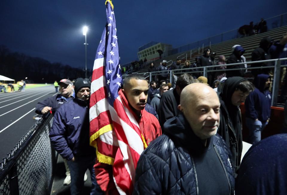 Firefighter Evandres Conjura carries a flag during a vigil for Spring Valley Firefighter Jared Lloyd at Spring Valley High School March 23, 2022. Lloyd died March 23, 2021, during a fire at the Evergreen Court Home for Adults.