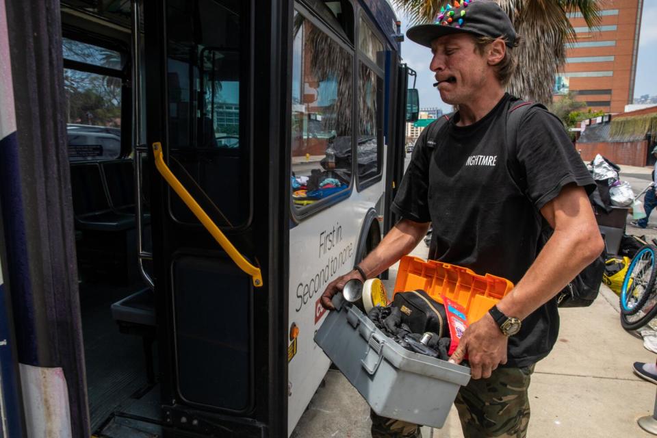 A man carries his belongings onto a bus