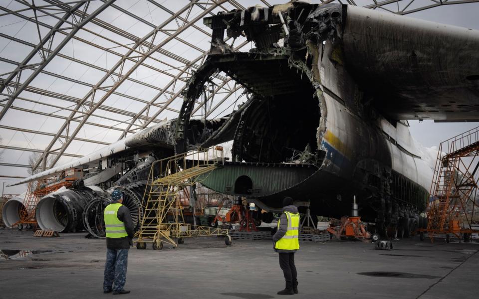 Airport workers look at the gutted remains of the Antonov An-225, the world's biggest cargo aircraft, destroyed during fighting between Russian and Ukrainian forces, at the Antonov airport in Hostomel, on the outskirts of Kyiv, Ukraine, Saturday, April 1, 2023. (AP Photo/Efrem Lukatsky) - AP Photo/Efrem Lukatsky