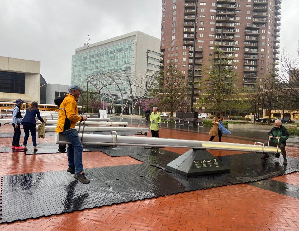 Attendees of a media event in Des Moines for the new interactive art installation, "Impulse," play on the seesaws on April 18, 2024.