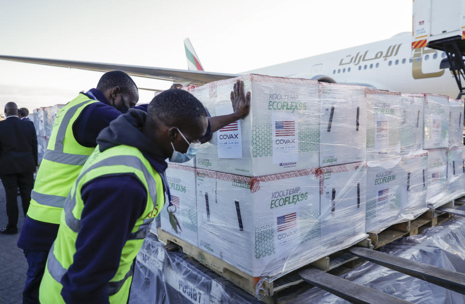 An airport worker stands next to boxes of Moderna coronavirus vaccine after their arrival at the airport in Nairobi, Kenya Monday, Aug. 23, 2021. The first time that Moderna COVID-19 vaccines have been received in Kenya, 880,460 doses were delivered forming the first of two shipments totalling 1.76 million doses which were donated by the U.S. government via the COVAX facility, according to UNICEF who transported the vaccines. (AP Photo/Brian Inganga)