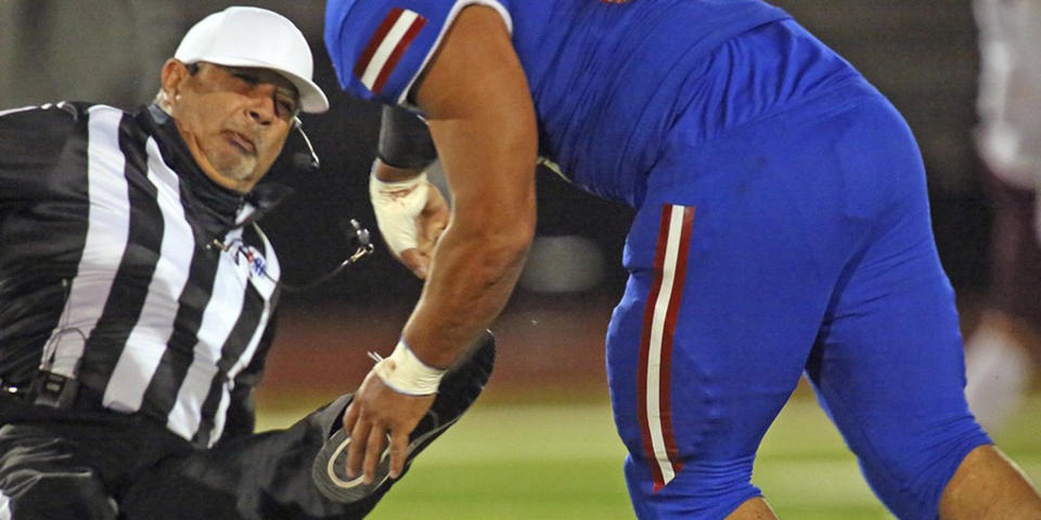 Football referee Fred Gracia falls to the turf after being charged by Edinburg's Emmanuel Duron. (Joel Martinez / The Monitor via AP)