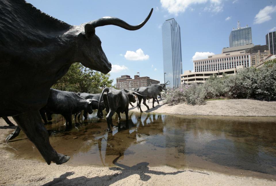 This Aug. 7, 2009 photo shows an outdoor longhorn steer sculpture in downtown Dallas with the Dallas skyline in the background. Dallas is a city that likes to do things big, but that doesn’t mean you’ll have to sell the ranch to have a good time here. (AP Photo/Tony Gutierrez)