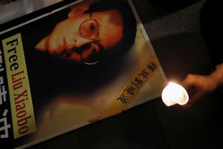A protester holds a candle next to a portrait of Chinese Nobel rights activist Liu Xiaobo demanding his release, during Chinese President Xi Jinping visiting, ahead of 20th anniversary of the city's handover from British to Chinese rule, in Hong Kong, China June 29, 2017. REUTERS/Tyrone Siu/Files