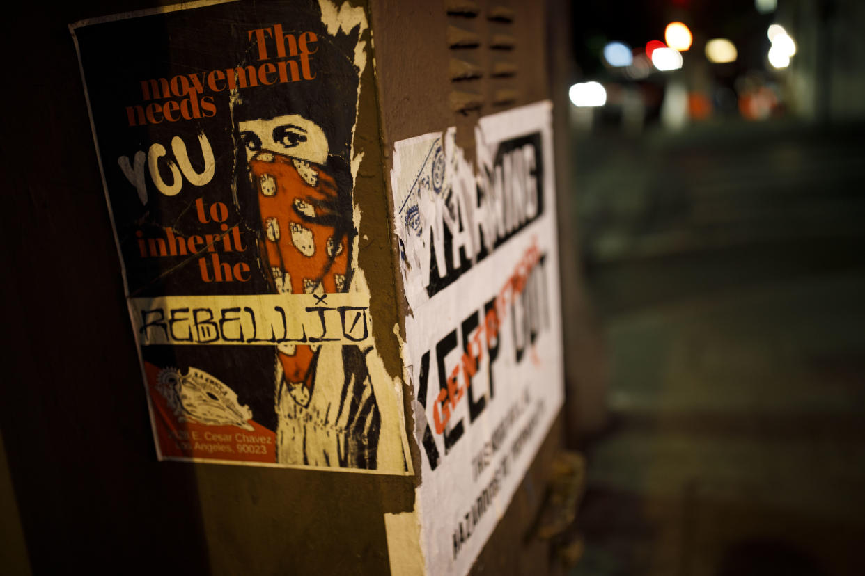 Posters on a Boyle Heights, Los Angeles, utility box state, “The Movement Needs You To Inherit The Rebellion” and “Warning – Gentrifiers Keep Out – This Hood Will Be Hazardous to Your Health.” (Photo: Patrick T. Fallon for Yahoo News)