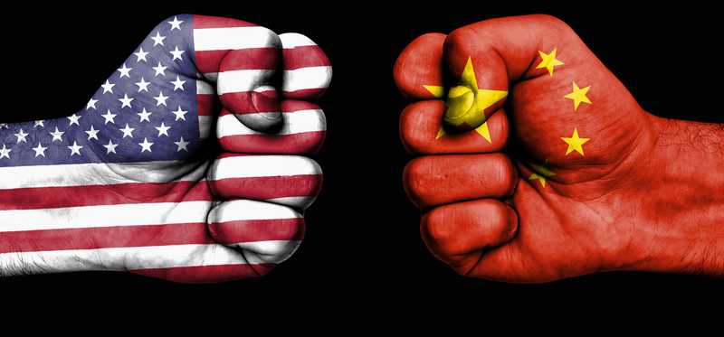 Two clenched fists aimed at each other, one painted with U.S. flag and the other with China's flag.