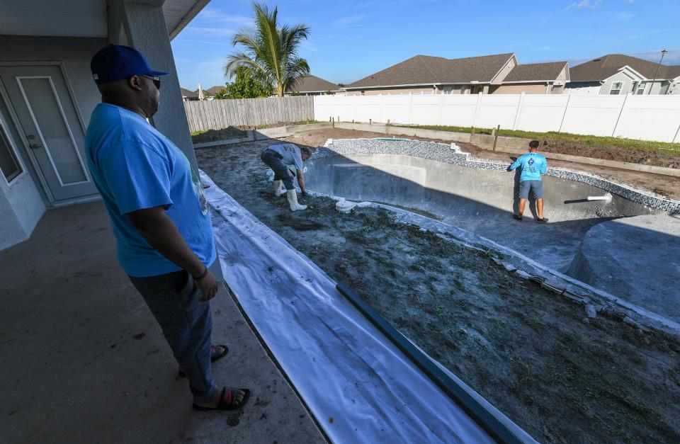 Homeowner Nathaniel Webb (from left) watches Vitali and Daniel Bederak, of Pools by Vitali, as they work on Wednesday, Oct. 20, 2021, retiling the pool started by Amore Pools, at Webb's home in the Torino development in Port St. Lucie. "They got to work right away," Webb said. "Been getting a lot done. They kind of had to correct some things that Amore messed up."