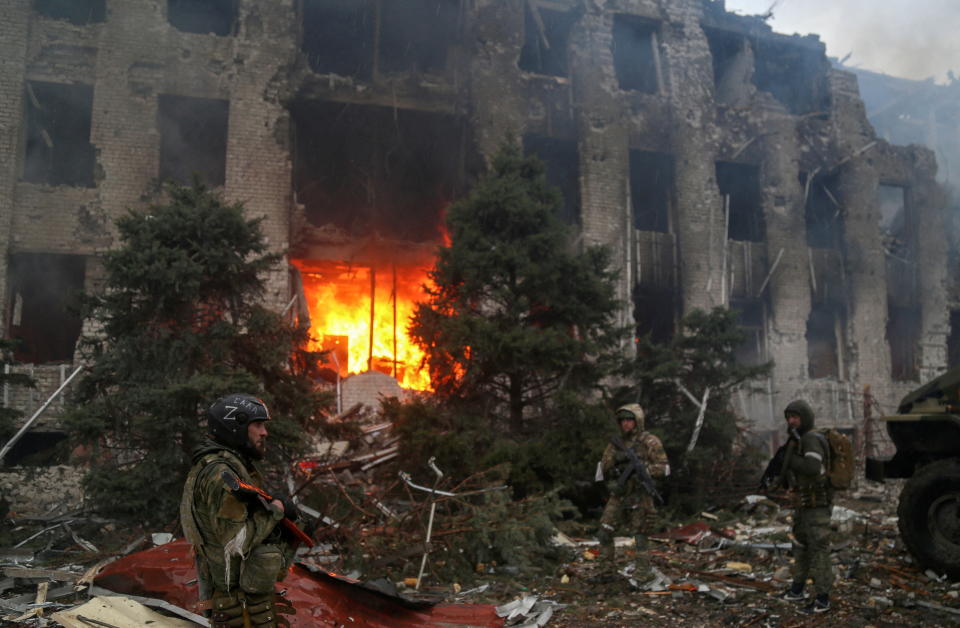 Pro-Russian troops stand in front of the burned Azovstal building