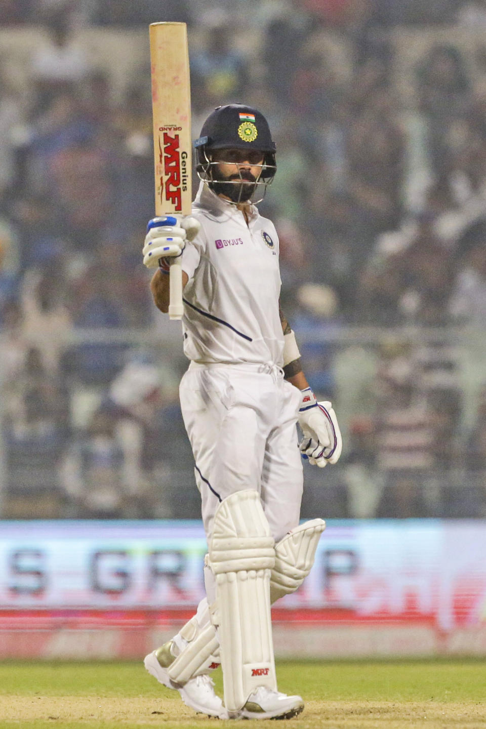 Indian cricket captain Virat Kohli raises his bat after scoring fifty runs during the first day of the second test match between India and Bangladesh in Kolkata, India, Friday, Nov. 22, 2019. (AP Photo/Bikas Das)