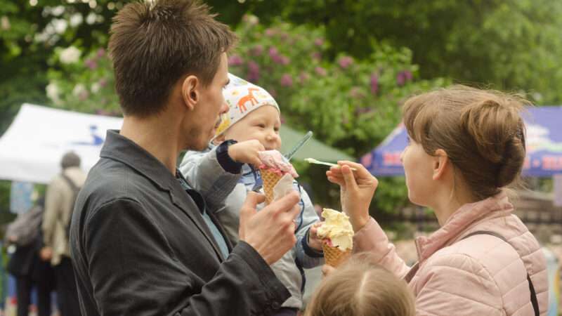 A young couple feeds ice cream to their infant.