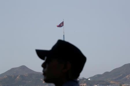 A South Korean soldier stands guard as a North Korean flag flutters on top of a tower at the propaganda village of Gijungdong in North Korea, in this picture taken near the truce village of Panmunjom, South Korea, September 28, 2017. REUTERS/Kim Hong-Ji/Files