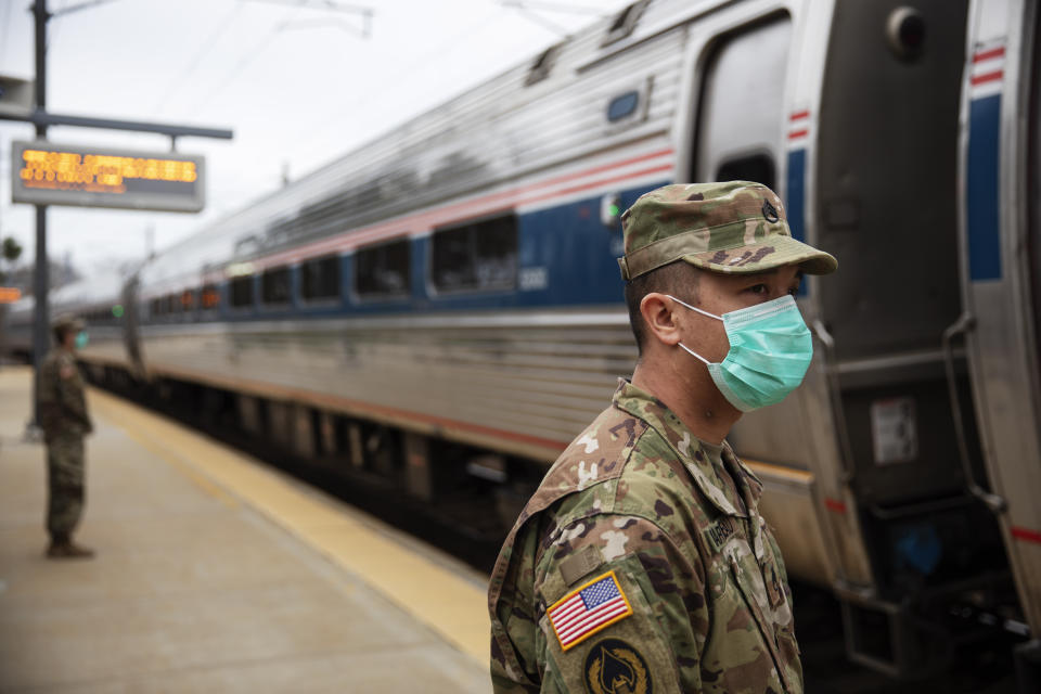 Members of the Rhode Island National Guard look for passengers getting off from a train from New York as it arrives Saturday, March 28, 2020, in Westerly, R.I. States are pulling back the welcome mat for travelers from the New York area, which is the epicenter of the country's coronavirus outbreak, and some say at least one state's measures are unconstitutional. Gov. Gina Raimondo ratcheted up the measures Friday afternoon, announcing she'll also order the state National Guard to go door-to-door in coastal communities starting this weekend to find out whether any of the home's residents have recently arrived from New York and inform them of the quarantine order. (AP Photo/David Goldman)