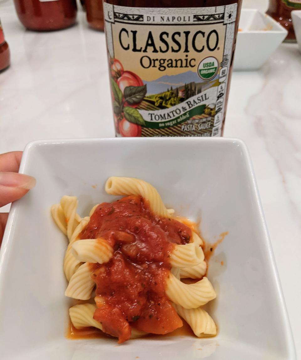 Jar of classico red sauce behind a small white bowl of pasta