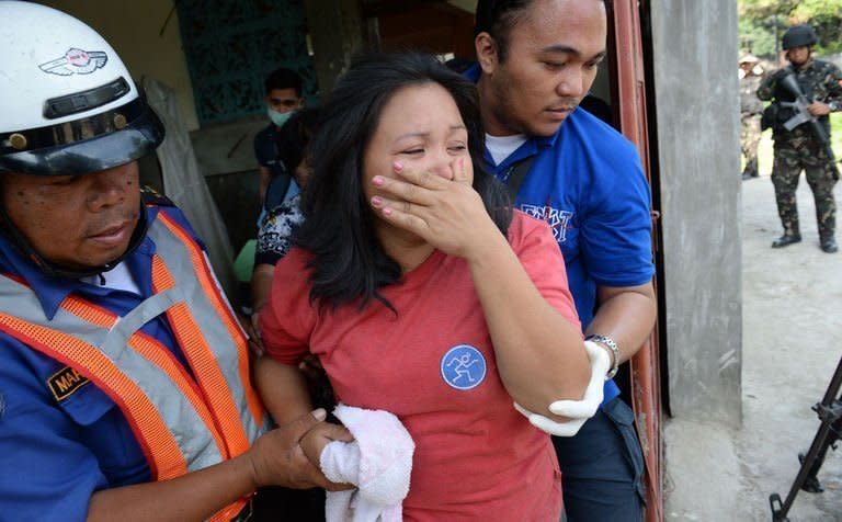 An injured resident is helped by rescuers after a mortar shell hit her house in Zamboanga, on the southern island of Mindanao, on September 21, 2013. Philippine President Benigno Aquino has flown out of the southern city where troops are fighting Muslim rebels, saying he expects the deadly battles to be over soon