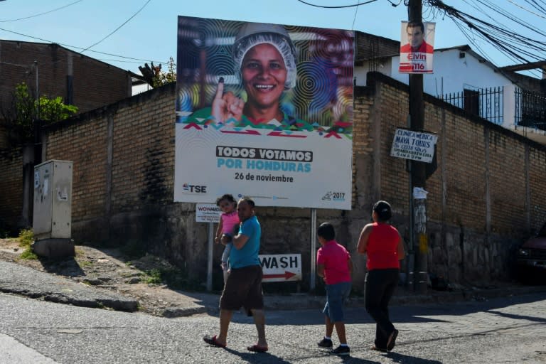 A family walks past a billboard encouraging Hondurans to vote in Sunday's presidential election in the capital Tegucigalpa