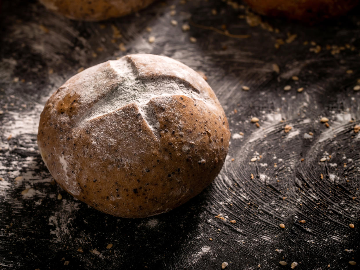 The rustic loaf of bread placed on wooden black background. Close-up buns with sunlight in the morning.