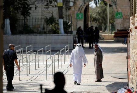 Palestinians walk next to the entrance of the compound known to Muslims as Noble Sanctuary and to Jews as Temple Mount at morning after Israel removed the new security measures there, in Jerusalem's Old City July 25, 2017. REUTERS/Ronen Zvulun