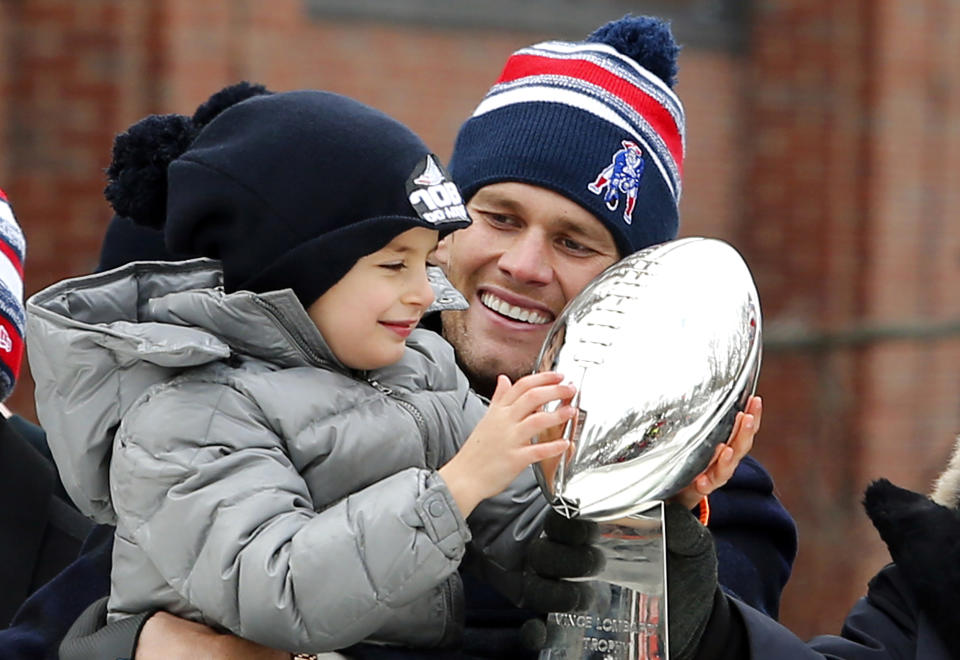 El quarterback de los Patriots, Tom Brady, sonríe mientras su hijo Benjamin sostiene el trofeo Vince Lombardi en el desfile de campeones del Súper Bowl el miércoles, 4 de febrero de 2015, en Boston. (AP Photo/Winslow Townson)