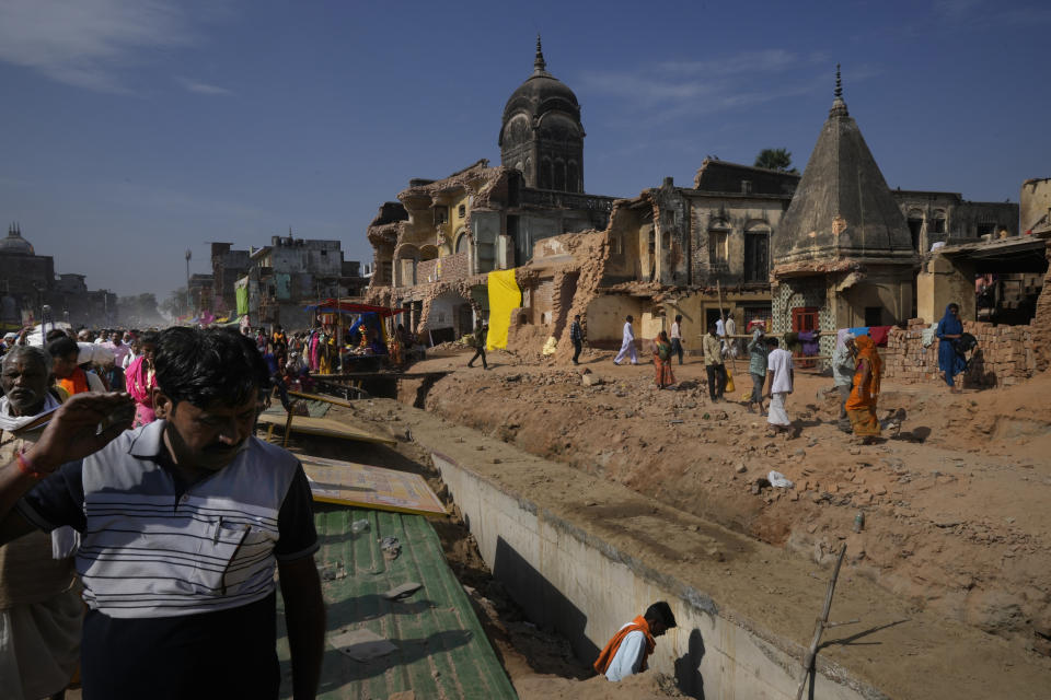 Devotees walk beside a row of demolished buildings to make wider roads under city redevelopment, in Ayodhya, India, March 30, 2023. Ayodhya is taken over by frenetic construction of hotels, bringing in tens and thousands of Hindu pilgrims. Tired construction workers are busy cutting through buildings on the roadsides to make way for wider highways. (AP Photo/Manish Swarup)