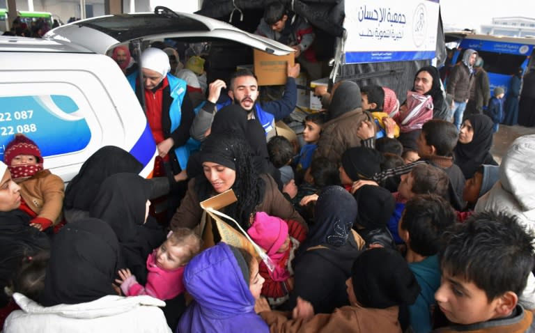 Syrians who fled from rebel-held areas in east Aleppo receive aid food on December 1, 2016, at a warehouse in a small village on the city's eastern outskirts More than 50,000 Syrians have joined a growing exodus of terrified civilians from the besieged rebel-held east of Aleppo, the Syrian Observatory for Human Rights monitor said, as the UN Security Council was set for emergency talks on fighting in the city