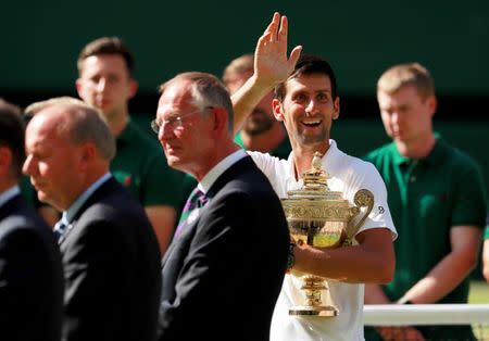 Tennis - Wimbledon - All England Lawn Tennis and Croquet Club, London, Britain - July 15, 2018 Serbia's Novak Djokovic waves to his family as he celebrates with the trophy after winning the men's singles final against South Africa's Kevin Anderson. REUTERS/Andrew Couldridge