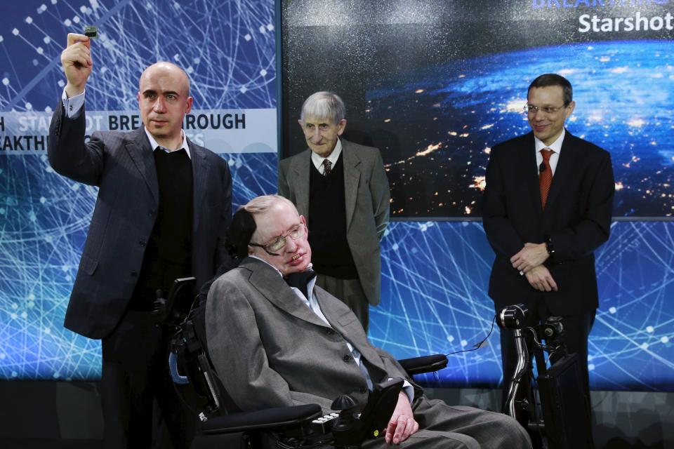 Avi Loeb stands to the right of Stephen Hawking and two other men onstage.