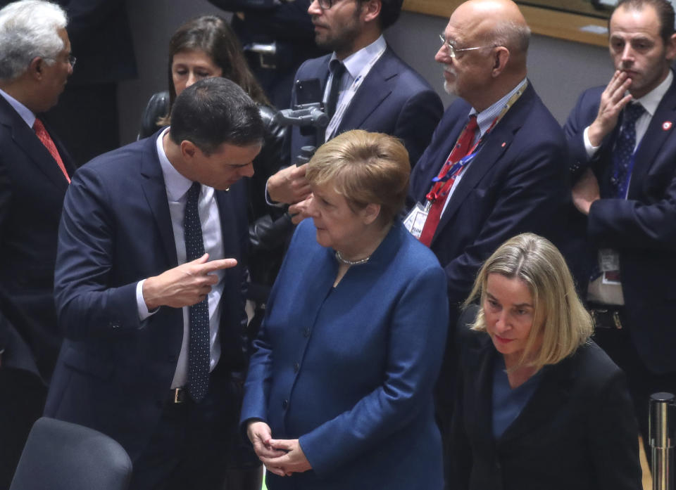 Spanish Prime Minister Pedro Sanchez, left, speaks with German Chancellor Angela Merkel, center, during a round table meeting at an EU summit in Brussels, Friday, Oct. 18, 2019. After agreeing on terms for a new Brexit deal, European Union leaders are meeting again to discuss other thorny issues including the bloc's budget and climate change. (Aris Oikonomou, Pool Photo via AP)