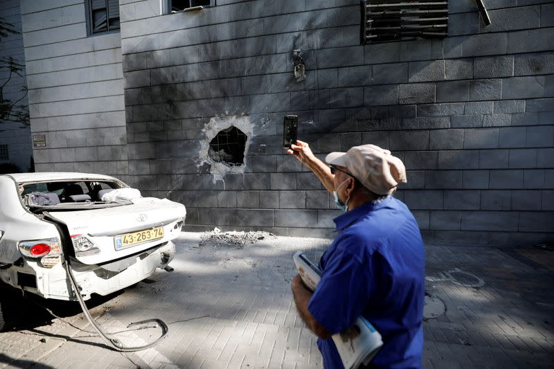 FILE PHOTO: An Israeli man takes a photo with his mobile phone at a residential building after a rocket launched overnight from the Gaza Strip hit it in Ashkelon, Israel