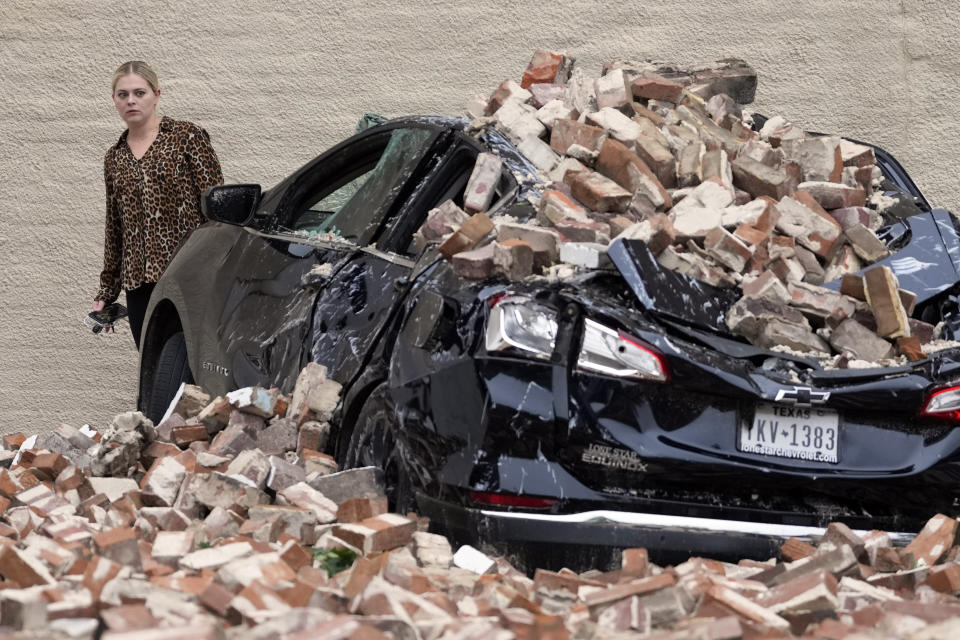 A woman looks at the damage caused by fallen bricks from a building wall in the aftermath of a severe thunderstorm Friday, May 17, 2024, in Houston. Thunderstorms pummeled southeastern Texas on Thursday, killing at least four people, blowing out windows in high-rise buildings and knocking out power to more than 900,000 homes and businesses in the Houston area. (AP Photo/David J. Phillip)